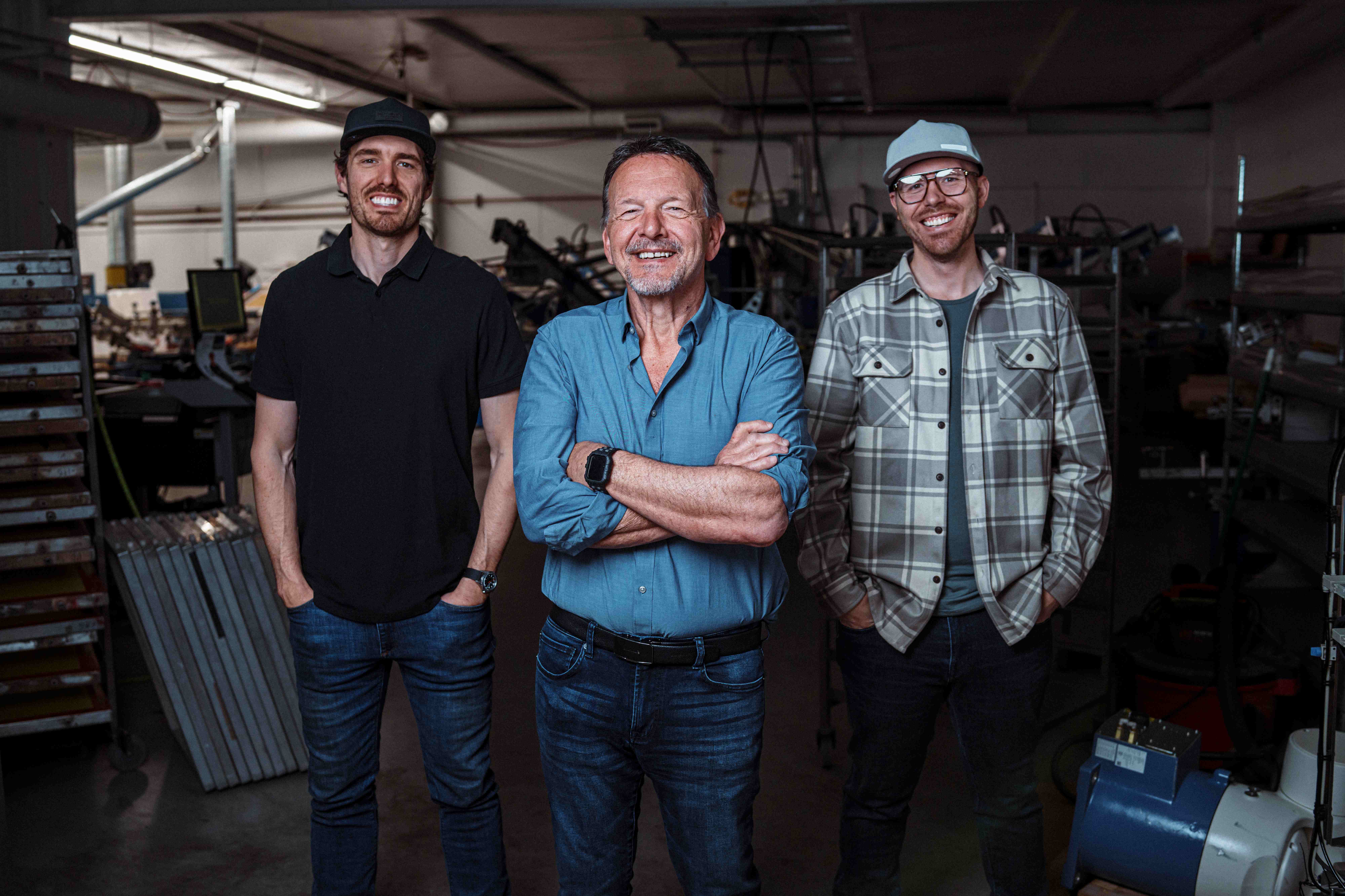 Three founders standing confidently in their manufacturing facility, representing the owner-operated businesses ScalePoint helps with M&A advisory